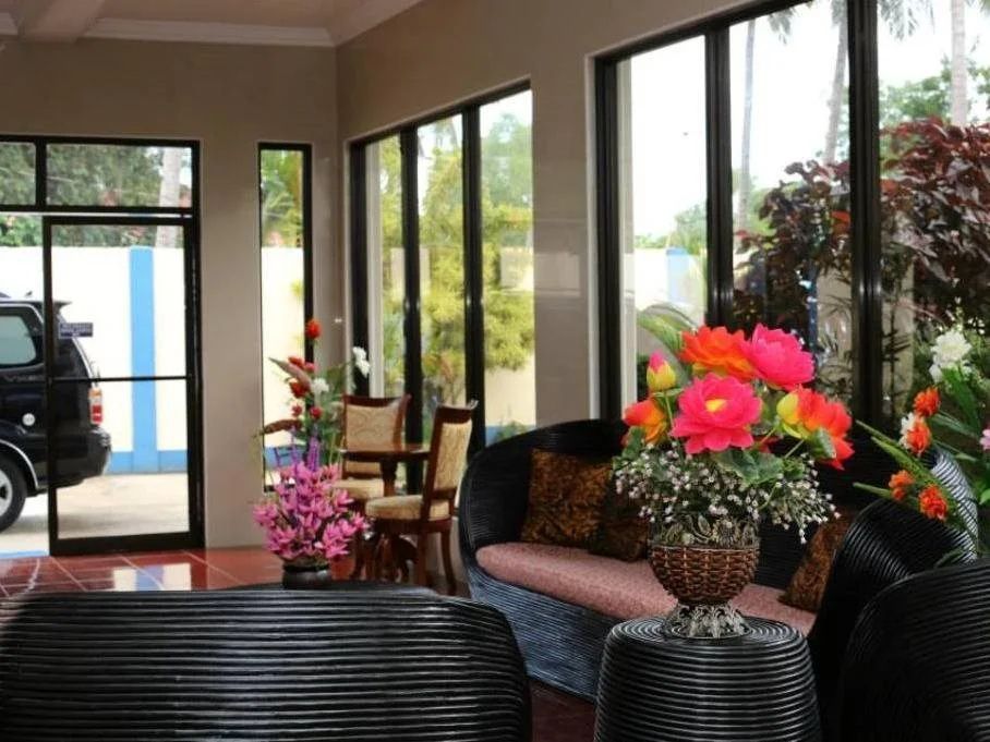 Lobby lounge with rattan sofas, a vase of pink flowers and tall windows