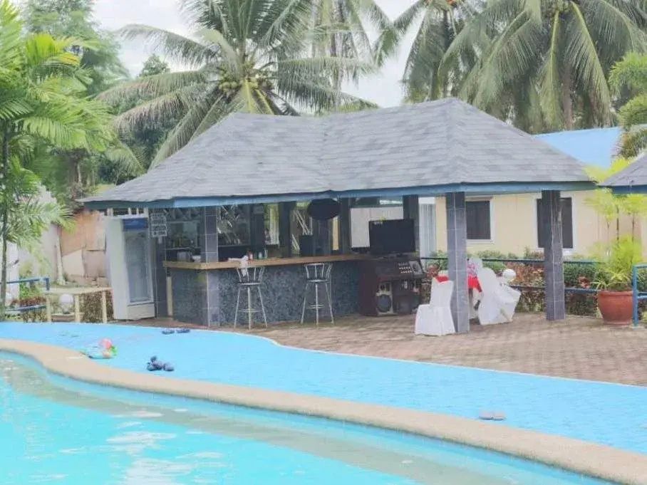 Pool bar under a grey tiled roof with stools, right at the pool's edge
