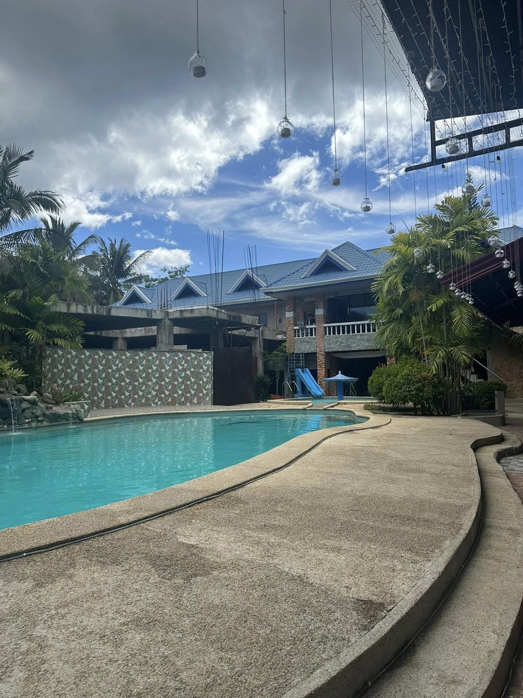 Curving pool edge in the foreground with the resort's two-storey wing and palms beyond