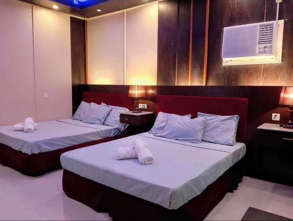 Twin Room with two double beds, maroon headboards and a blue-lit cove ceiling