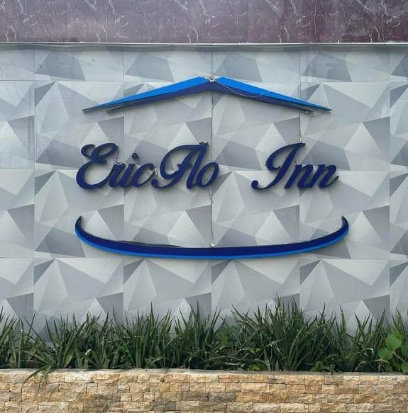 Blue script EricFlo Inn lettering under a roof-line motif on a white textured wall