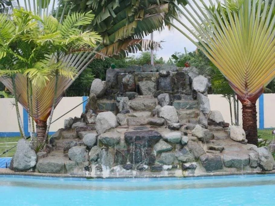 Stacked-rock waterfall flanked by traveller's palms, spilling into the pool